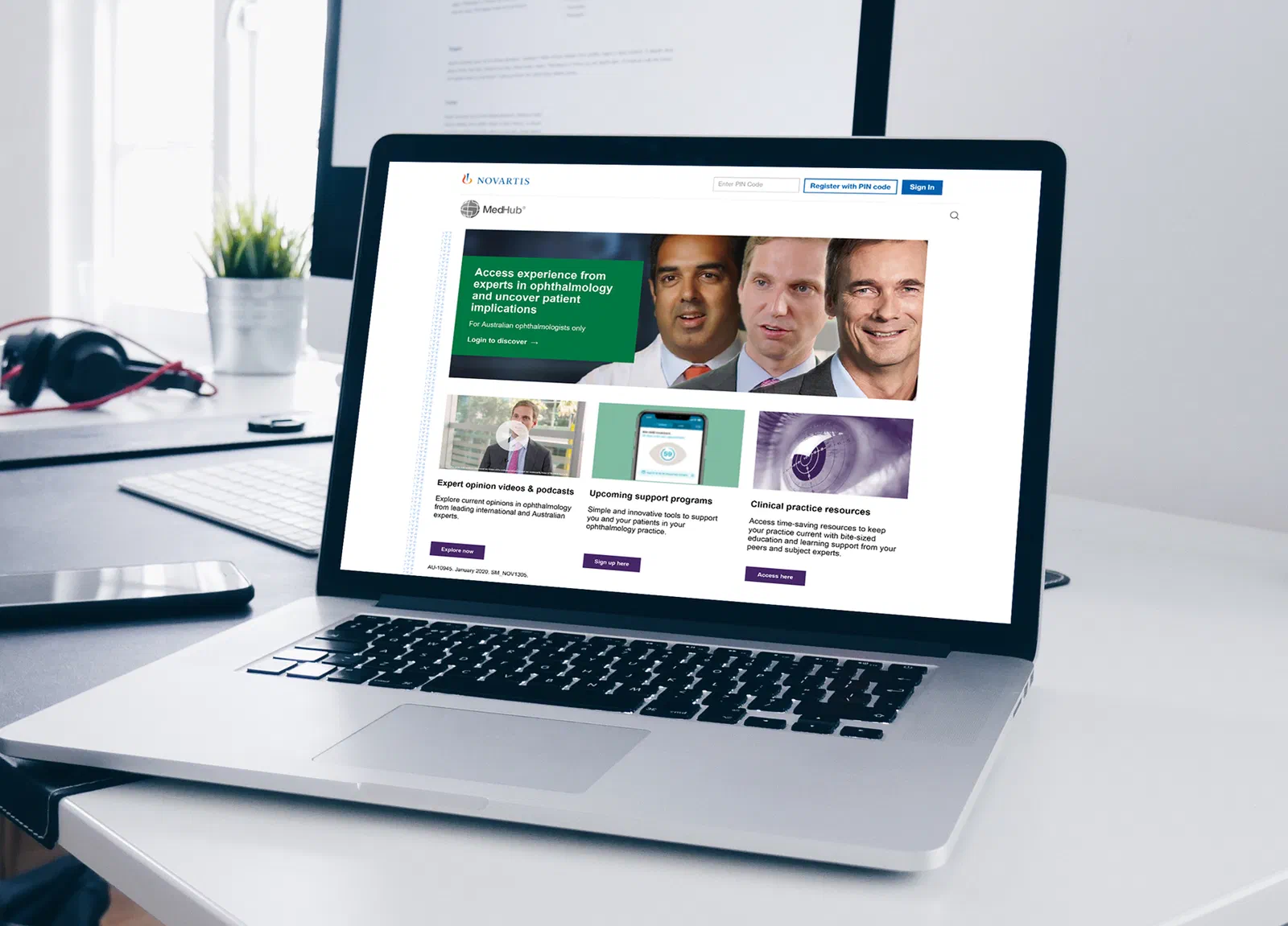 A laptop on a desk displaying the MedHub homepage: the ophthalmology hero banner, Register/Sign In controls and three content tiles for expert opinion videos, support programs and clinical practice resources